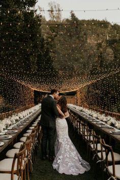 a bride and groom standing at the end of a long table