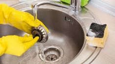 a person in yellow gloves is cleaning a sink