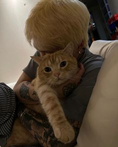 a woman with blonde hair holding a cat on her lap and looking at the camera