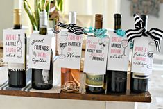 several wine bottles with labels on them sitting on a table next to some glasses and flowers