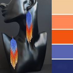 a pair of earrings with orange, yellow and blue beads hanging from it's sides