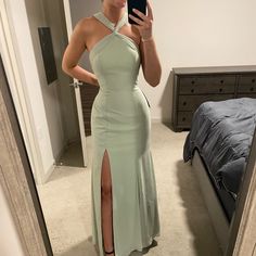 a woman taking a selfie in a mirror wearing a green dress and high heels