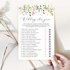 a person holding up a wedding checklist with flowers on the top and below it