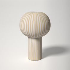 a white and beige striped vase sitting on top of a table