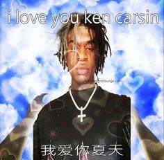 a man with dreadlocks standing in front of a blue sky and clouds, wearing a t - shirt that says i love you ken carism