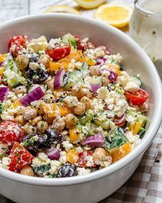 a white bowl filled with salad next to sliced lemons and a glass of milk