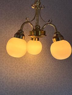 three lights hanging from a ceiling in a room with wallpapered walls and flooring