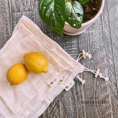 two lemons sitting on top of a cloth next to a potted green plant