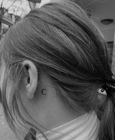 a woman's left ear has a small crescent tattoo on the back of her right ear