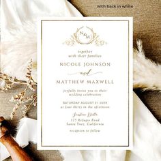 a wedding card with an elegant design and gold foil on the front, along with some feathers