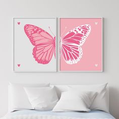 two pink and white butterfly prints on a wall above a bed