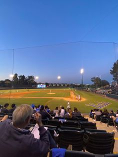 people are sitting in the bleachers watching a baseball game on a sunny day