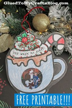 an ornament that has been made to look like a coffee mug with a christmas tree in the background