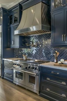 a large kitchen with blue cabinets and stainless steel stove top oven in the center, along with wooden flooring