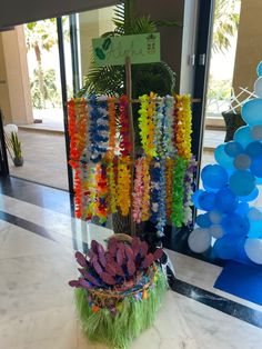 a vase filled with lots of different colored flowers on top of a marble floor next to balloons