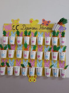 a bunch of cups that are sitting on a wall with bunny ears and carrots in them