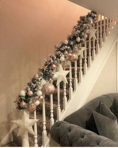 a christmas garland on the banister next to a stair case with star decorations and baubies