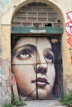 an open door with graffiti on it and a woman's face painted on the side