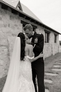 a bride and groom kissing in front of an old stone building on their wedding day