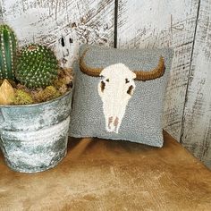 a cow head pillow sitting on top of a table next to a potted cactus