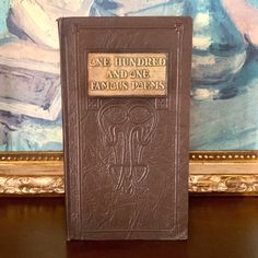 a brown book sitting on top of a wooden table in front of a wall painting