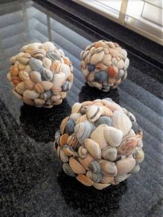 three seashell balls sitting on top of a black table next to a glass window