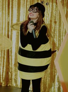 a woman in a bee costume holding a microphone