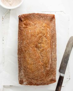 a loaf of bread sitting on top of a cutting board next to a knife and bowl