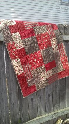 a red and white quilt hanging on a fence