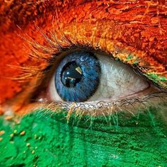 an eye with green, orange and blue colors painted on it's irises