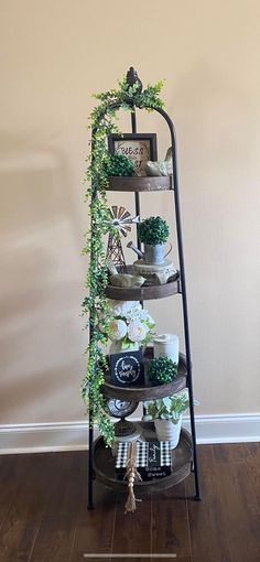 a tall metal shelf filled with potted plants and greenery on top of a hard wood floor