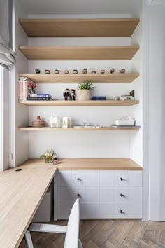 a desk and shelves in a room with wooden floors, white walls and wood flooring