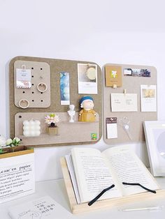 an open book sitting on top of a table next to a cork board with magnets