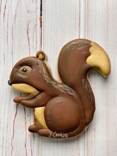 a brown and yellow squirrel ornament sitting on top of a white wooden fence