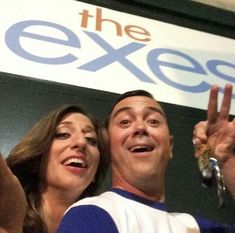 a man and woman standing next to each other in front of the exes sign