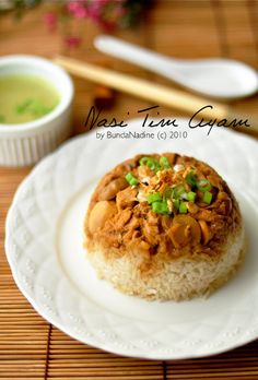 a white plate topped with rice covered in meat and veggies next to chopsticks