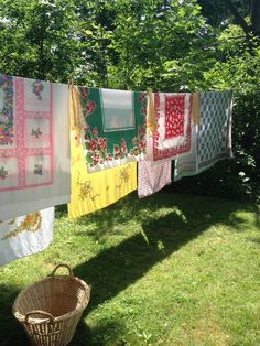 several colorful towels hanging on a clothesline in the grass next to a wicker basket