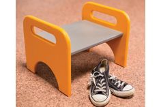 a pair of black and white shoes sitting next to an orange step stool