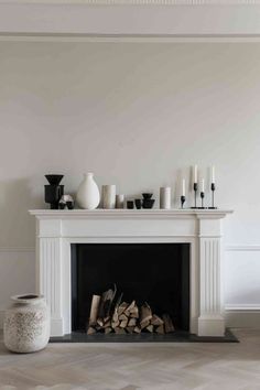 a white fireplace with candles and vases on top