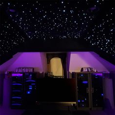 a room filled with lots of purple lights and books on the shelves in front of it