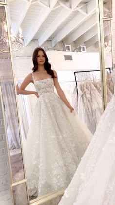 a woman standing in front of a mirror wearing a wedding dress