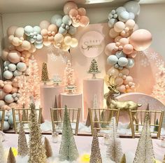 a table topped with lots of balloons and christmas trees next to a wall covered in snowflakes