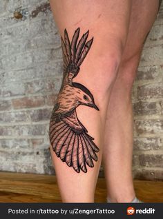 a woman's leg with a bird tattoo on it