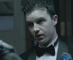 a man in a tuxedo looks at the camera while wearing a boutonniere