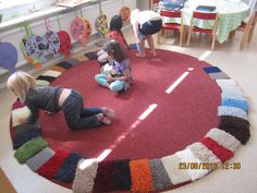 three children are playing on the floor in a room with colorful rugs and chairs