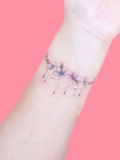 a woman's wrist tattoo with flowers on the left side of her arm and an arrow in the middle