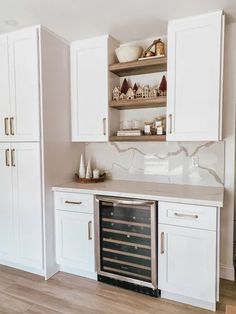 a kitchen with white cabinets and an open wine cooler