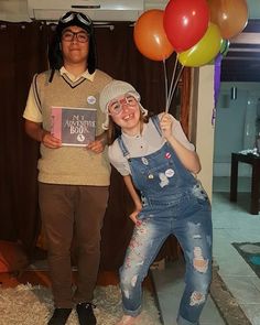 two people standing next to each other with balloons in the air and one person holding a book