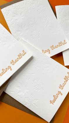 four white cards with gold lettering on them sitting on an orange surface next to each other