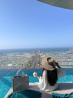 a woman sitting on top of a swimming pool next to a handbag and purse